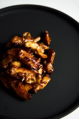 Chicken Tocino. Chicken in gooey sweet glaze. Caramelised chicken thighs in sweet sauce on black plate.