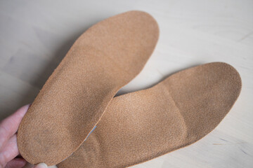 orthopedic insoles for shoes brown, made of natural materials, lies on a light surface of the table. Prevention and treatment of flat feet, shoe accessories