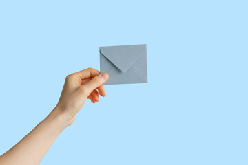 hand holds an envelope on a pastel background. isolated background with hand and letter. message and message concept.
