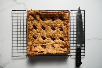 Uncuted Blondie with pecan nuts after baking. Top view of white chocolate sweet and tasty, chewy cookie bars.