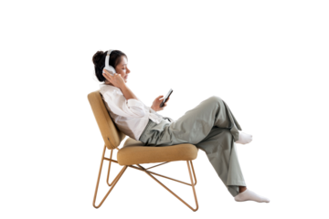 Listening to an audiobook playlist, a woman is resting on a chair using wireless headphones and an app in her phone, transparent background, isolated.