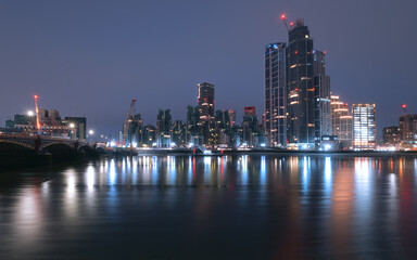 Panoramic view of London with the River Thames and skyscrapers in the lights near Vauxhall Bridge before dawn. London, United Kingdom