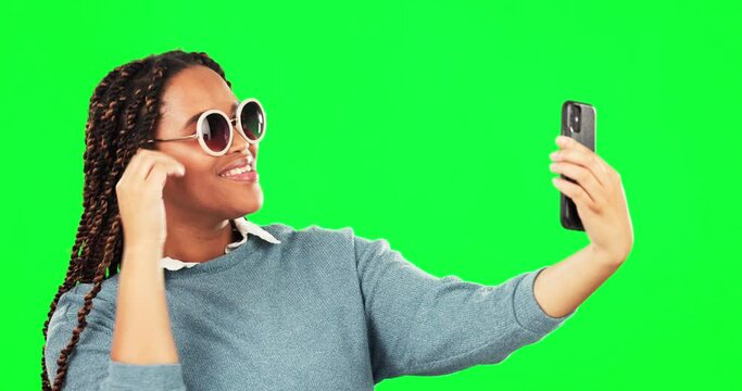 Selfie, sunglasses and attitude with a woman on a green screen background in studio for a profile picture. Photograph, fashion and style with a cool young female posing for social media status update