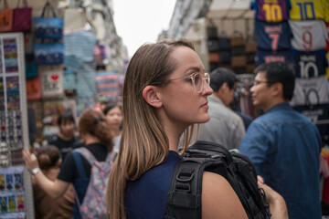Fototapeta premium This image shows a female tourist carrying a bag and walking through busy Asian streets.