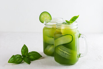 Cucumber water with basil and lemon in a glass mug on light table.