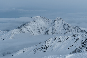 Fototapeta na wymiar Snowy mountains in the clouds. Beautiful landscape with snowy rocks