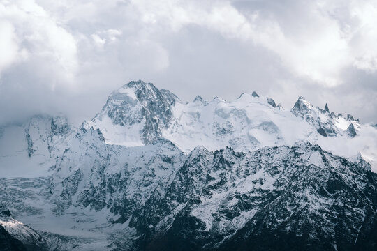 Alpine landscape with peaks covered with snow and clouds
