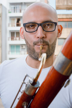 closeup portrait of young latino man playing the basson and looking at the camera