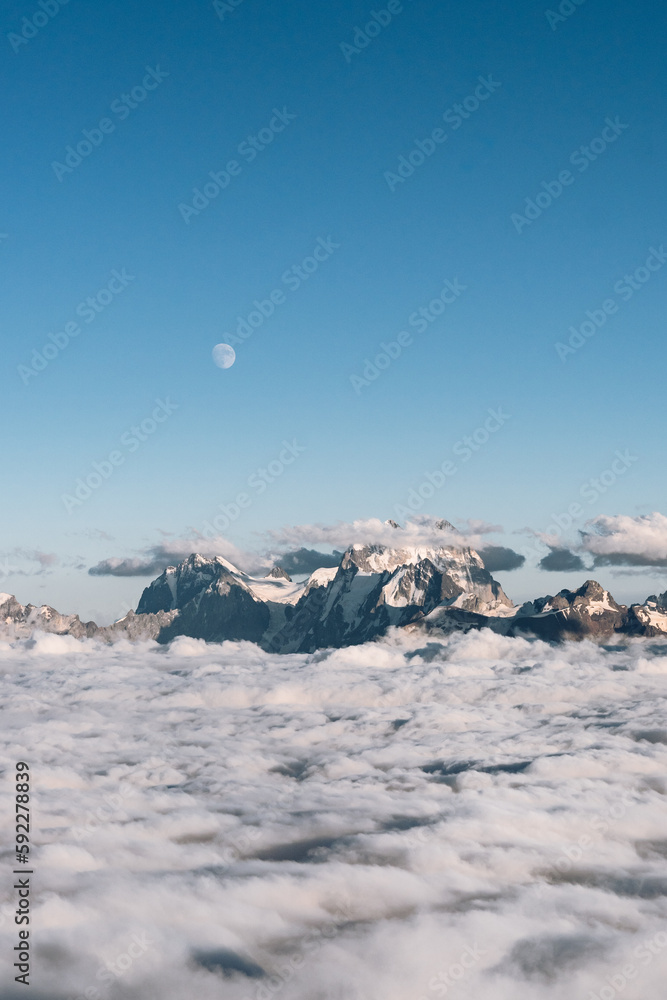 Wall mural view of the moon and the caucasian ridge with mount ushba above the clouds