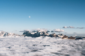 View of the moon and the Caucasian ridge with Mount Ushba above the clouds