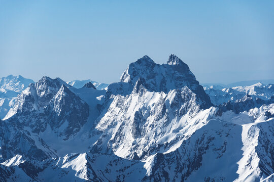 View of Mount Ushba and snow-covered peaks on a cloudy day from the top of Mount Elbrus