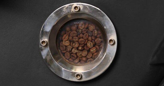 Close-up of the window of a coffee roaster. The coffee beans are roasted inside. The concept of coffee production.