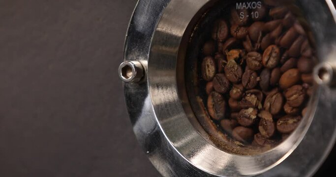 The coffee beans are moving and roasting in the industrial coffee roasting machine. Close-up. Modern equipment. Industrial cooking arabica and robusta.