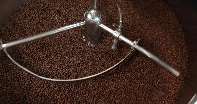 Shiny stainless large metal vat for roasting coffee beans close-up. Coffee beans are into it. The concept of industrial cooking arabica and robusta.