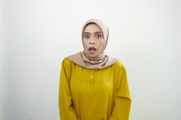 Fototapeta premium A portrait of a shocked Asian woman wearing a mustard casual dress, isolated by a white background