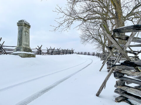 Headstone on snowy land with metal barriers at the Antietam National Cemetery in Maryland, USA