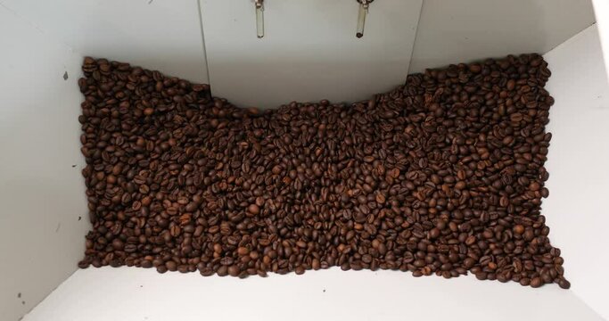 Close-up of coffee beans in a vat during roasting. Close-up. Innovative coffee roaster. Lots of coffee in the vat.