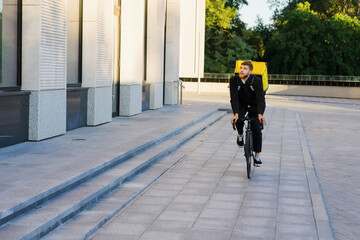 Velo courier rides along the building and looks for the address he needs. Delivery from restaurants. Delicious food