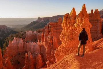 Vlies Fototapete Backstein Woman hiking on the Navajo Rim trail next to Thor Hammer during sunset in Bryce Canyon National Park, Utah, USA. Scenic golden hour view of Sandstone Hoodoos in Bryce Canyon Amphitheatre on sunny day