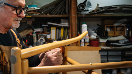 tanner gluing the leather parts to a chair made by hand in a small shop in rome center. traditional work