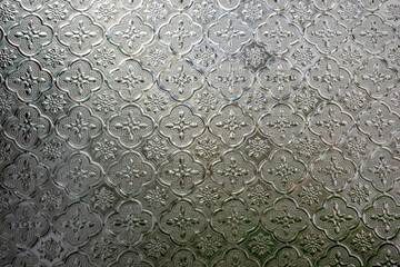 Texture of a milky pane of glass. Glass background with floral pattern and symmetrical ornaments.
