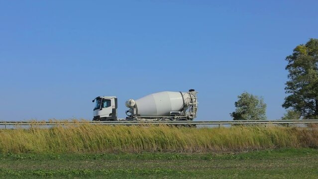 The concrete mixer rides on the highway. A truck with concrete is driving along the highway. Transportation of concrete by truck