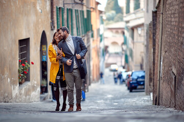 A young couple in love is enjoying emotional moments while walking the old city. Walk, rain, city,...