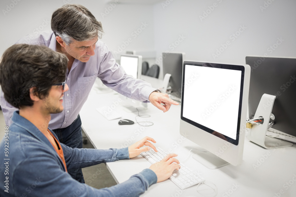 Poster businessman pointing at computer while explaining colleague
