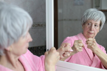 Senior woman ready to fight her mirror reflection 