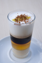 Traditional Canarian coffee Barraquito with separated layers of milk condensed and liquor on blurred background.