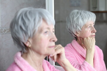 Profile of senior woman thinking with her own reflection 