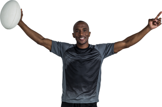 Confident sportsman with arms raised holding rugby ball