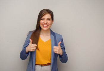 Smiling excited woman in blue business suit shows two thumbs up. Isolated portrait of student or...