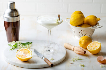 Elderflower gin sour with lemon and freshly picked elderberry flowers. Refreshing floral spring cocktail with elderflower cordial syrup