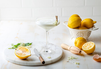 Elderflower gin sour with lemon and freshly picked elderberry flowers. Refreshing floral spring cocktail with elderflower cordial syrup