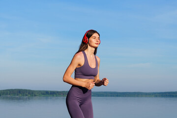 Portrait of a young woman running along the beach in a tracksuit. Outdoor training