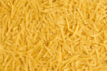Yellow background with raw vermicelli noodles. Concept - pasta as background.