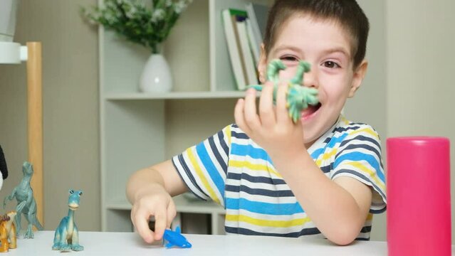 A 5-year-old boy plays dinosaur toys while sitting at a table in the children's room.
