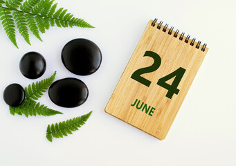 June 24. 24th day of the month, calendar date. Notepad, black SPA stoneJune s, green leaves. Summer month, day of the year concep