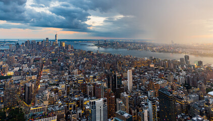 A rain storm over the illuminated lower Manhattan in New York City during beautiful sunset. 