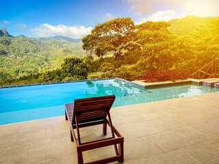 Lounger beside an infinity pool overlooking a jungle valley with mountains in the background.