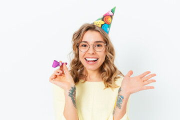 Happy young woman in party cap holding kazoo
