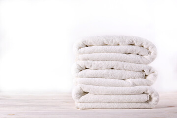 Stack of neatly folded towels on a rustic wooden table, waiting to be used. Showcase of a cozy...
