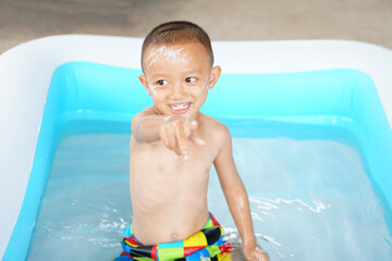 Hot weather. Boy playing with water happily in the tub.