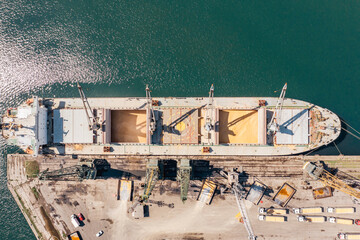 Aerial Top down view Black Sea port Loading of dry cargo ship with ukranian grain by cranes....