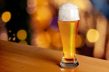 A glass of cold beer on table in bar background.