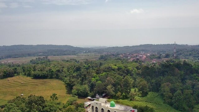 Aerial view of the mosque in the middle of the rice fields of the village taken by drone