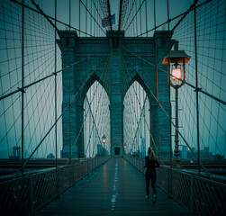 New York city view on Brooklyn Bridge at night with silhouette of a runner