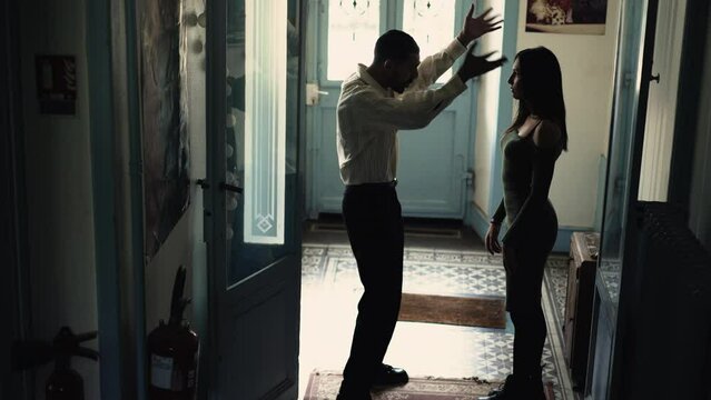 Candid couple discussing relationship at home. Dramatic moment of man and woman verbally fighting at front door entrance. People in crisis