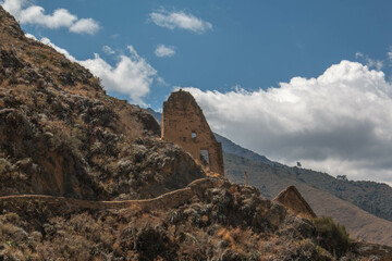 Fototapeta na wymiar Stone wall with square arched doorway at the archaeological site of Ollantaytambo with a blue sky with white clouds, in Peru.